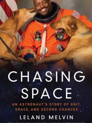 Book cover for Chasing Space: An Astronaut's Story of Grit, Grace, and Second Chances shows astronaut Leland Melvin in his orange spacesuit with his two large brown dogs