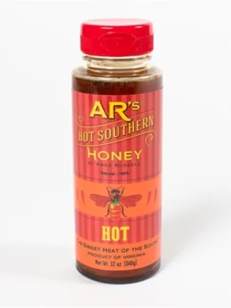 A bottle on a white background, with a red cap and a label with yellow text and a red bee. Text: AR’s® Hot Southern Honey by Ames Russell. HOT. The sweet heat of the South: Product of Virginia Net Wt. 12 oz. (340g)