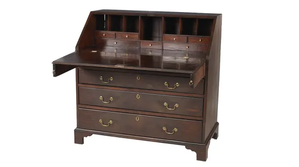 A dark wood desk with three long drawers with golden pulls and a desktop folded down to show a set of small drawers and mail slots