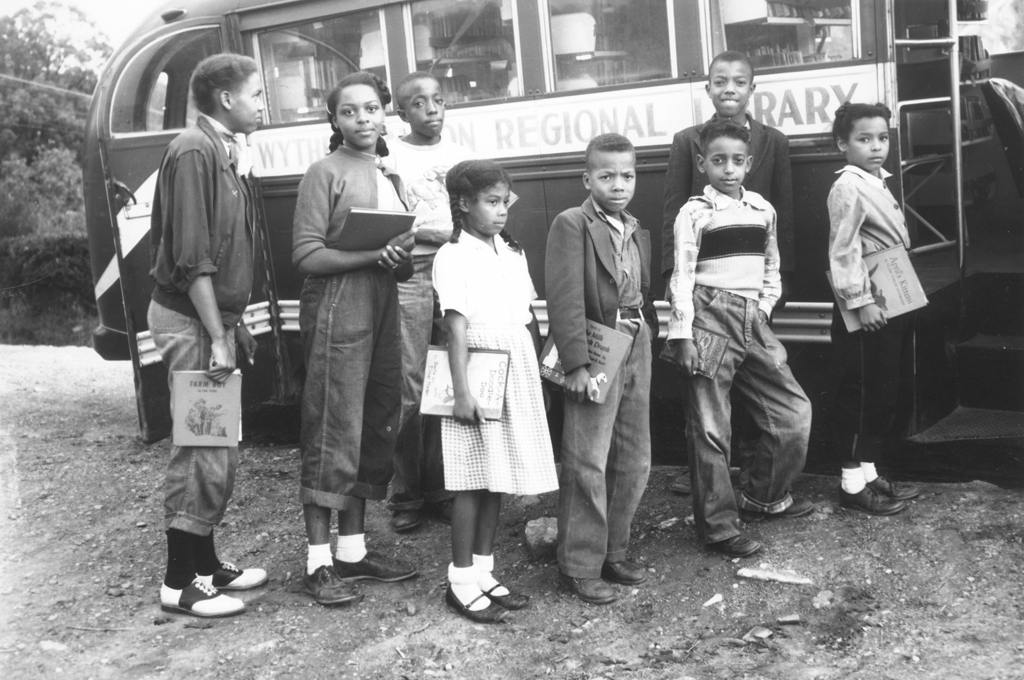 Black and white photograph of African American children holding books and waiting in line for the Bookmobile, Grayson County, 1954
