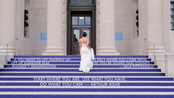 Bride walking up steps at VMHC. Steps have purple graphics with white words 