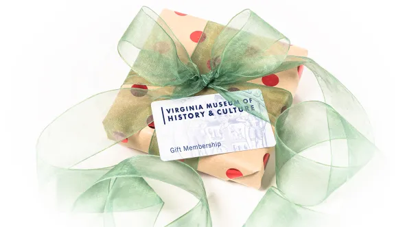 A wrapped box with ribbon has a gift card on top of it that says Virginia Museum of History & Culture Gift Membership
