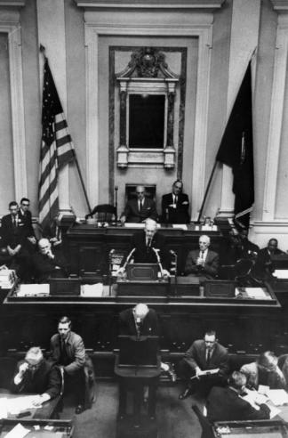 Black and white photograph of Governor J. Lindsay Almond standing in front of a podium addressing the General Assembly