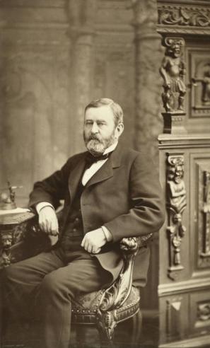 Vintage photograph of Ulysses S. Grant dressed in a suit and sitting in a chair at his desk