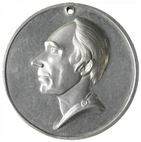A silver medalet with an engraving of Henry Clay’s side profile.     