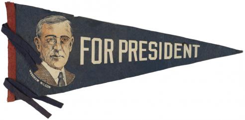 Blue pennant with a sketch drawing of Woodrow Wilson next to the words, “FOR PRESIDENT.” 