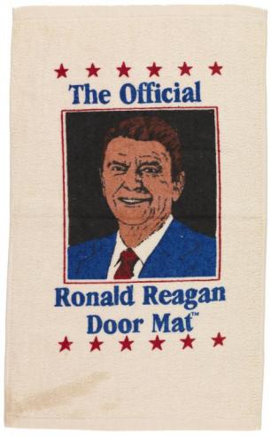 Tan door mat with a drawing of Ronald Reagan surrounded by red stars and the words, “The Official Ronald Reagan Door Mat,” in blue text. 